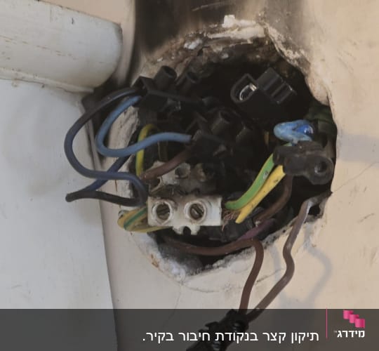 חוטי חשמל חשופים בקיר עם סימני שריפה